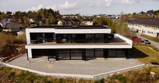Stort moderne hus med to etasjer og glassflater